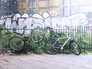 zwei fahrräder am Zaun vor Graffiti